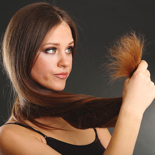 immagine di una ragazza che tiene in mano le punte dei sui capelli al quanto danneggiate